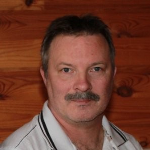 Mann mit Bart vor Holzwand